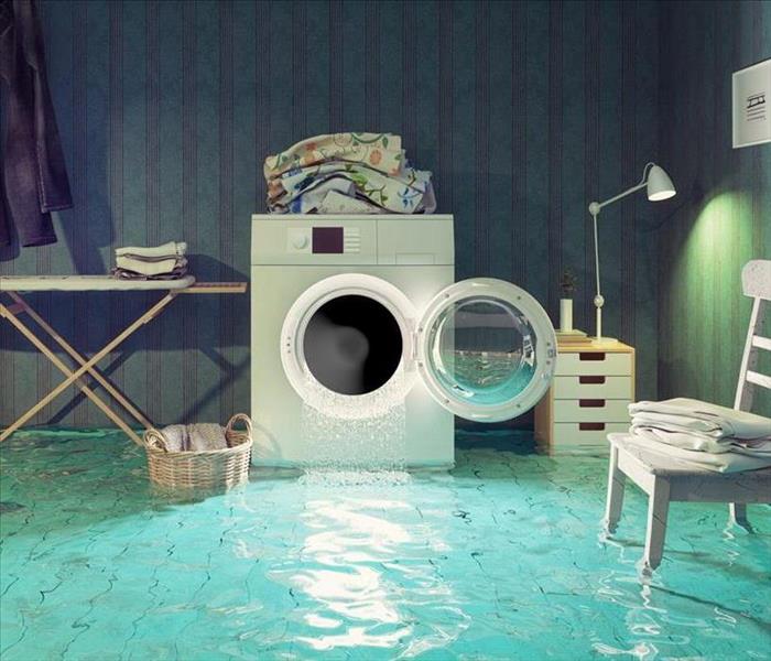 This picture is of a laundry room with water pouring out of the washer onto the floor.